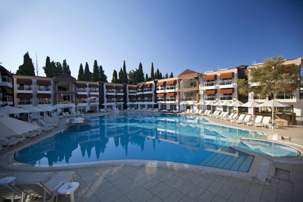 a large swimming pool with chairs and umbrellas at Bitez Risa Hotel in Bitez