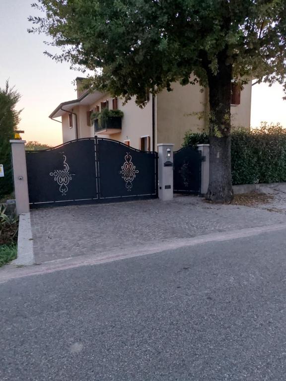 una cerca negra con un árbol delante de una casa en La Casa di M : D M., en Breda di Piave