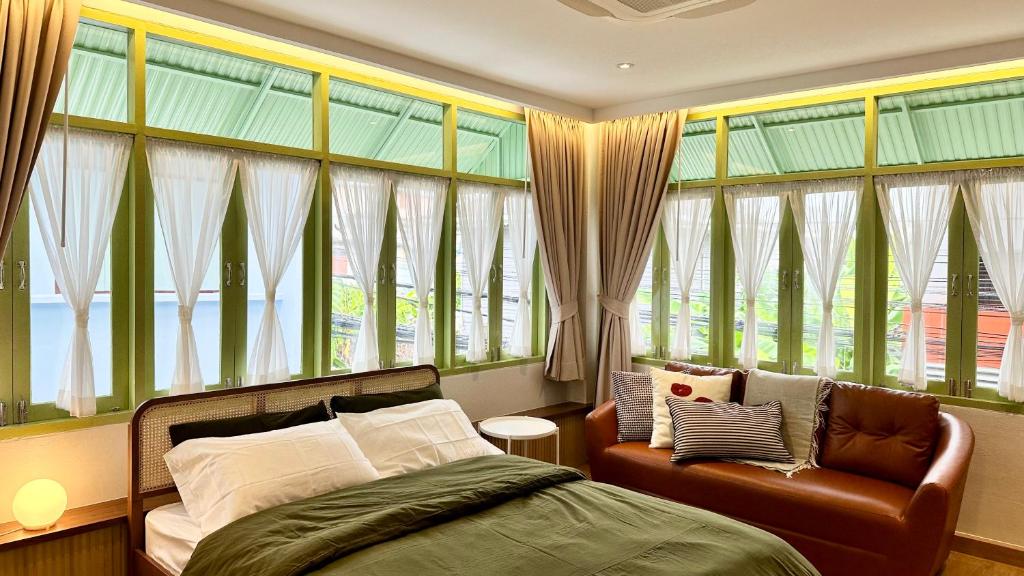 a bedroom with a bed and a chair and windows at The Tangerine Guesthouse in Bangkok