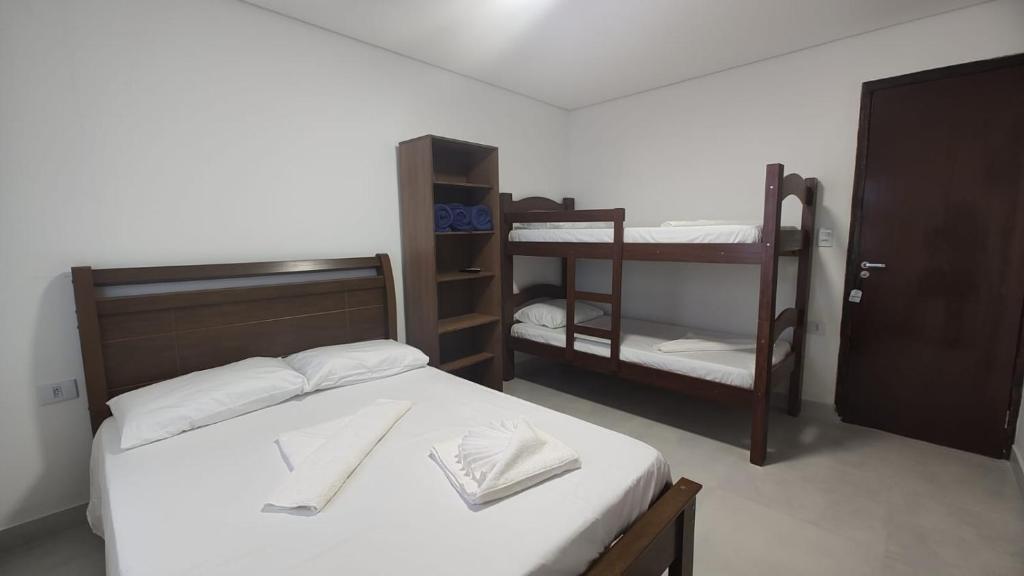 um quarto com uma cama e 2 beliches em Pousada Kasarão Praia Grande Ubatuba em Ubatuba