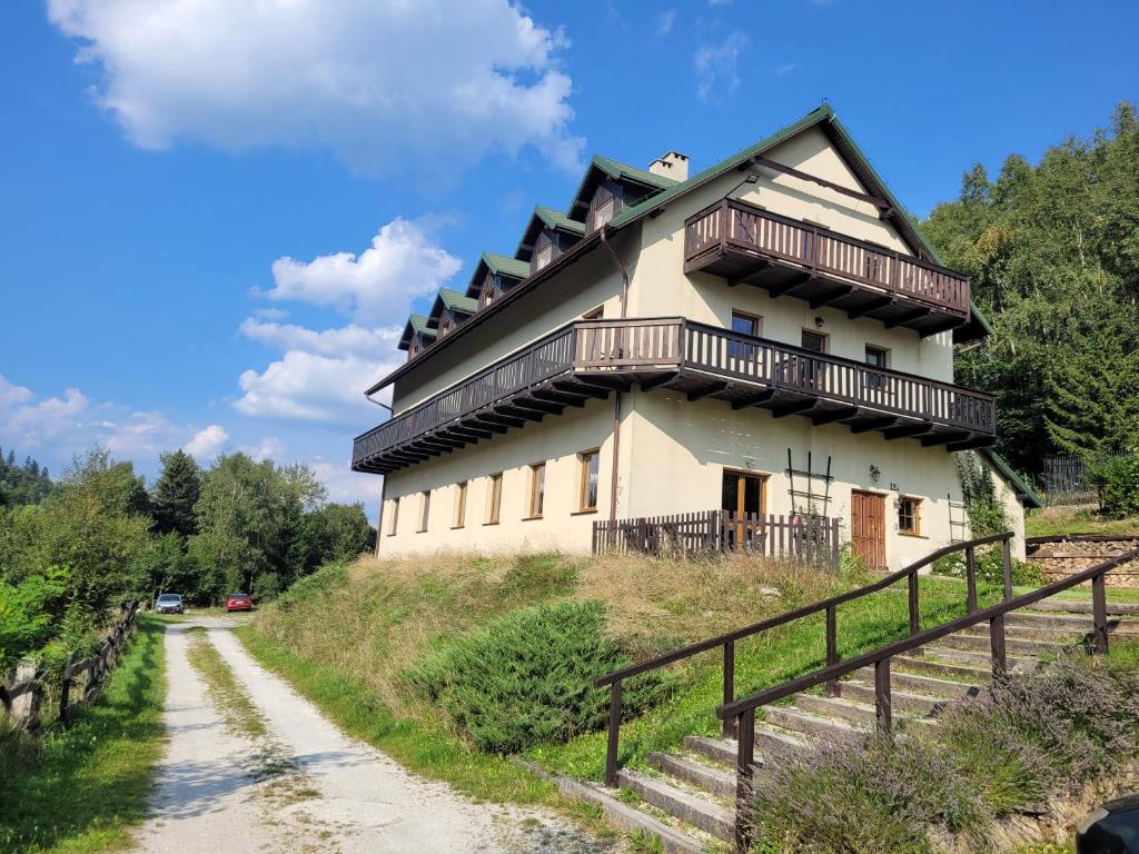 una casa en la cima de una colina con un camino de tierra en WILLA MONTE NEVE en Stronie Śląskie