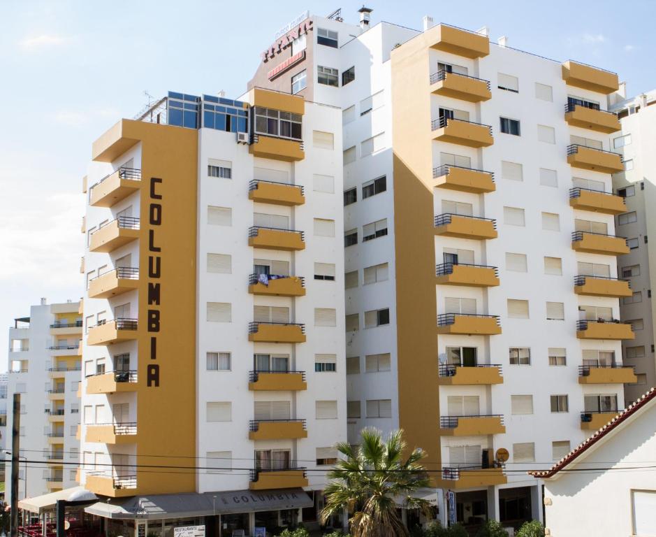 een hoog wit gebouw met gele balkons bij Columbia Apartamentos Turisticos in Portimão
