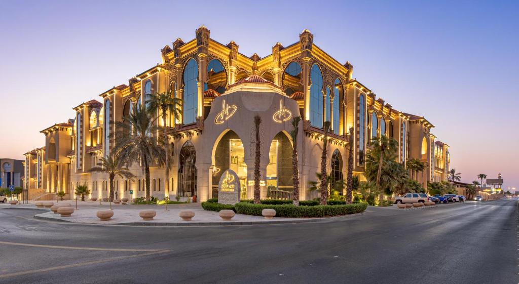 a large yellow building with palm trees in front of it at Madareem Hotel in Riyadh