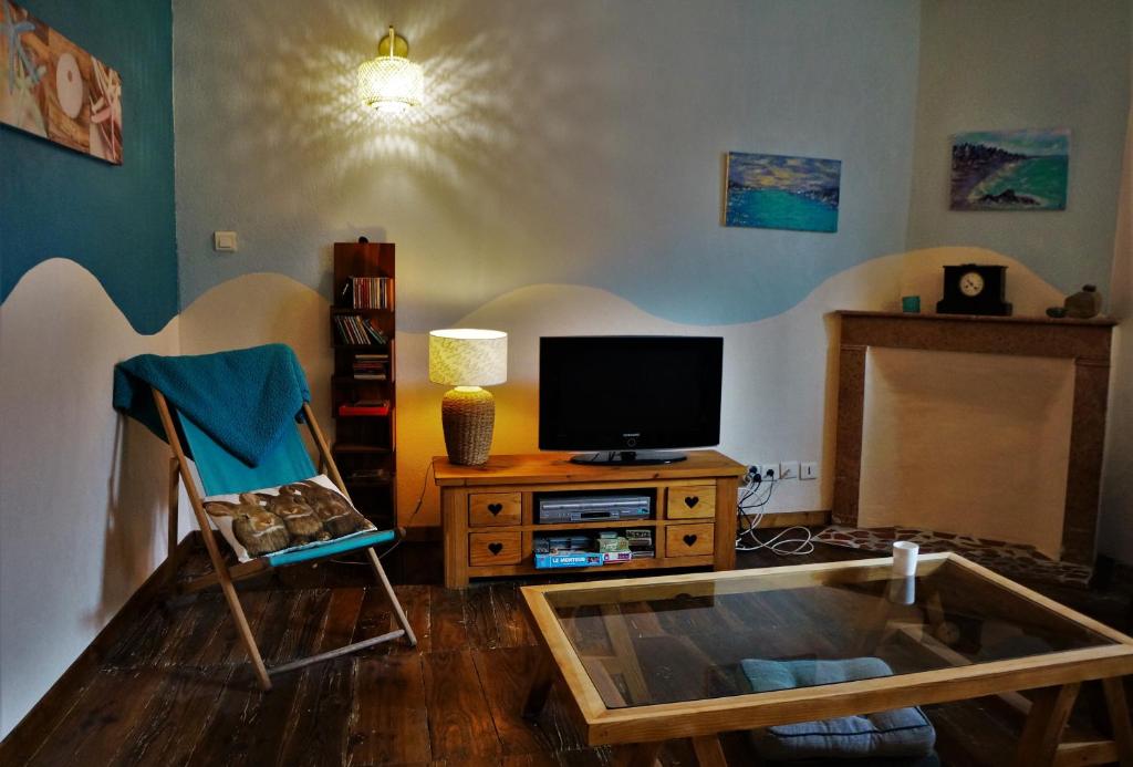 a living room with a tv and a glass table at La lanterne in Gap