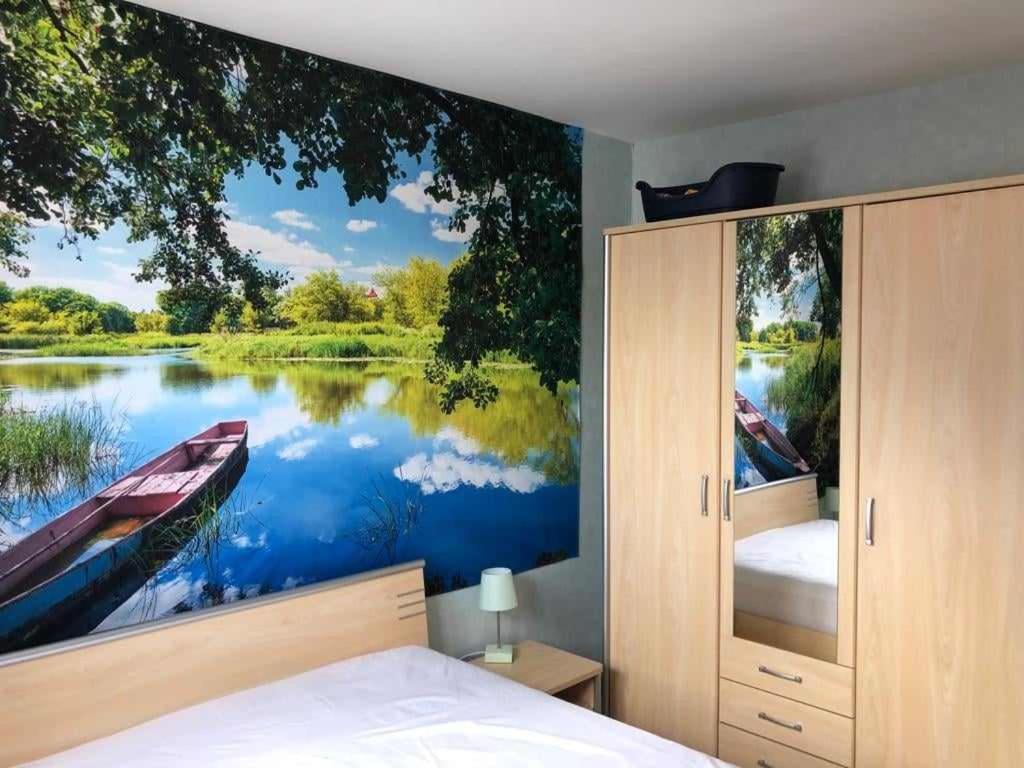 a bedroom with a large painting of a boat on a lake at La perle du Nord in Middelkerke
