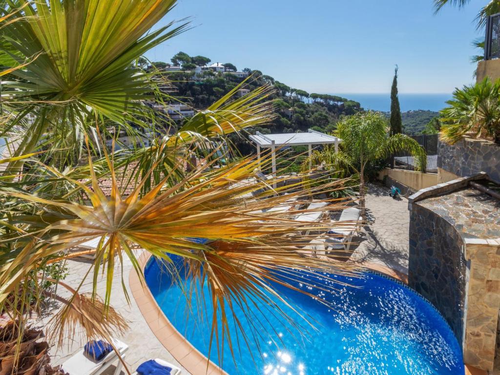 una piscina con palmeras y sillas en Holiday Home Floradise by Interhome, en Lloret de Mar