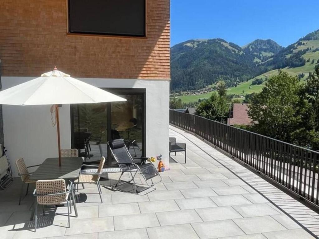 eine Terrasse mit einem Tisch, Stühlen und einem Sonnenschirm in der Unterkunft Apartment Gletscherhorn Sockelgeschoss Südwest by Interhome in Zweisimmen