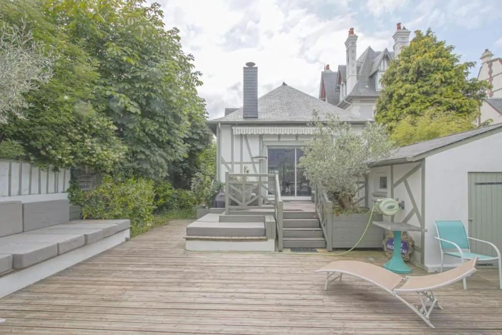 une terrasse en bois avec un banc et une maison dans l'établissement Maison ensoleillée centre de deauville, à Deauville