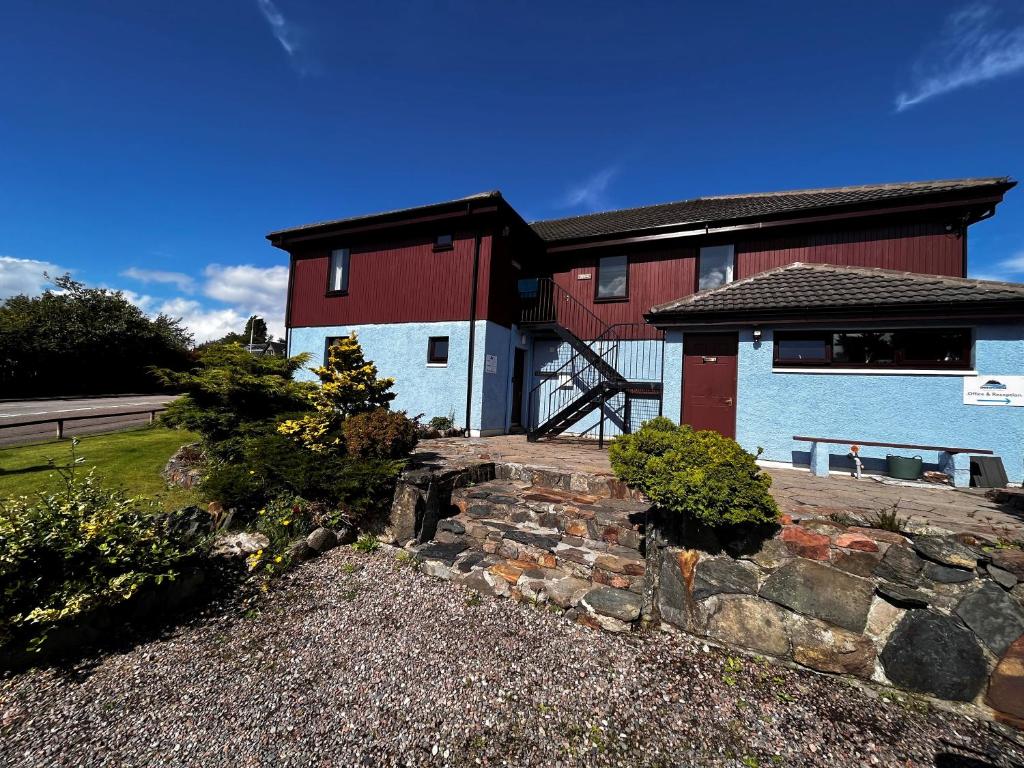 a large red and white house with a stone wall at Blacksmiths Bunkhouse in Fort William