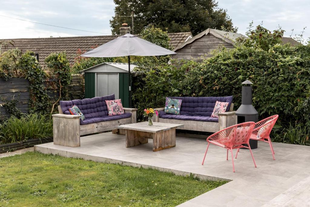 eine Terrasse mit 2 Sofas, einem Tisch und einem Sonnenschirm in der Unterkunft Stylish 2 bed pet-friendly coastal retreat in Braunton