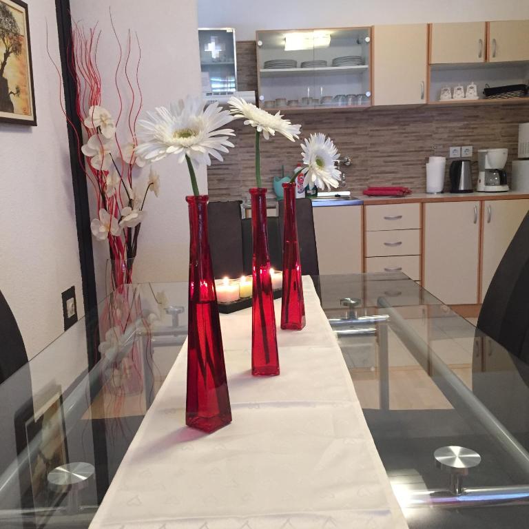 three red vases with white flowers on a table at Apartments Stakic in Krvavica