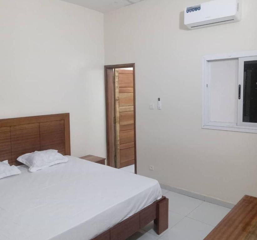 a white bedroom with a bed and a window at Salam in Saint-Louis