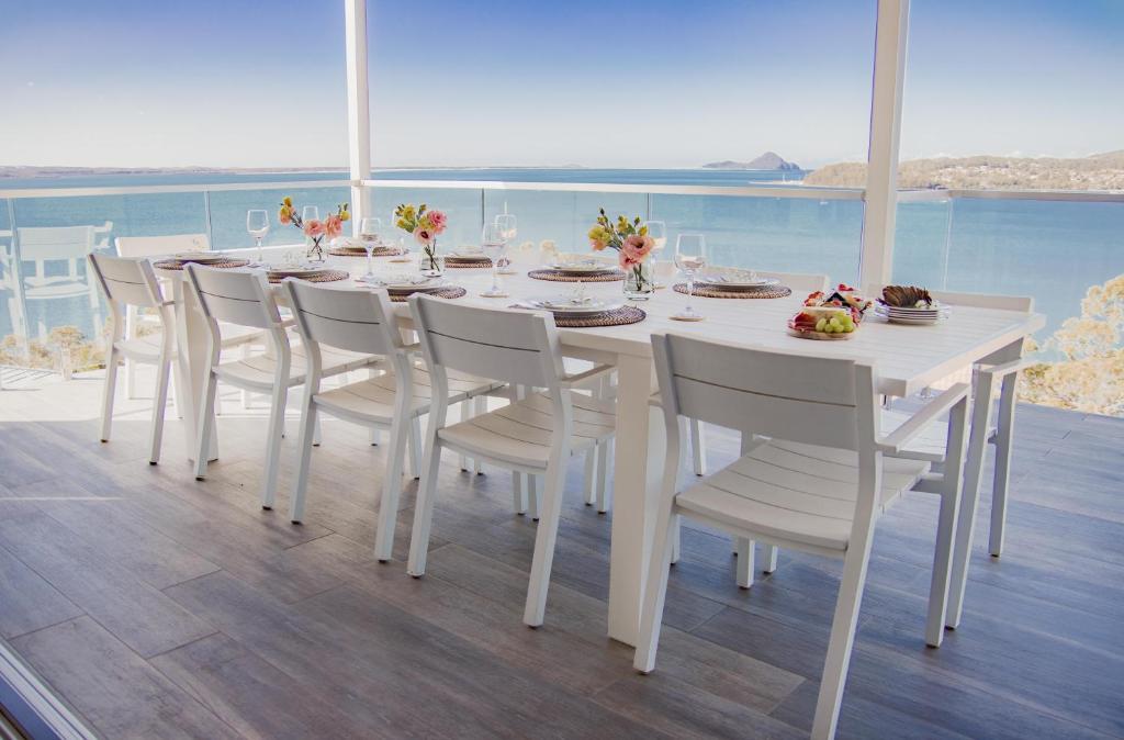 a white dining room table and chairs on a balcony at Bluewater Splendour - Heated infinity pool and amazing views!! in Salamander Bay