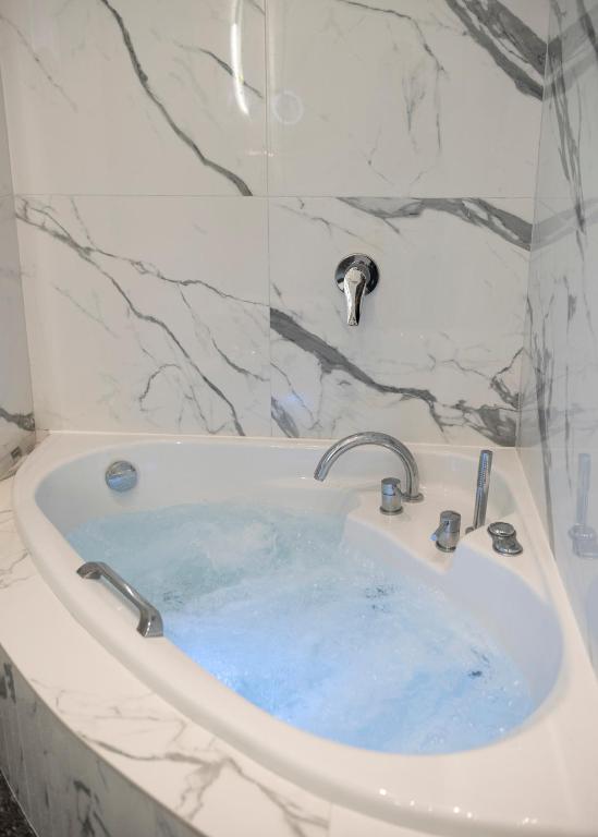 a bath tub filled with blue water in a bathroom at Jensen Luxury Suites in Rhodes Town