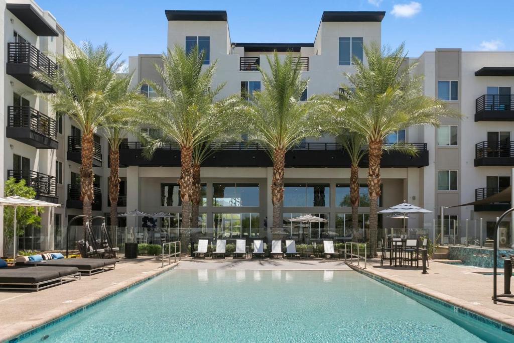 a swimming pool with palm trees in front of a building at Premium One and Two Bedroom Apartments at Slate Scottsdale in Phoenix Arizona in Scottsdale