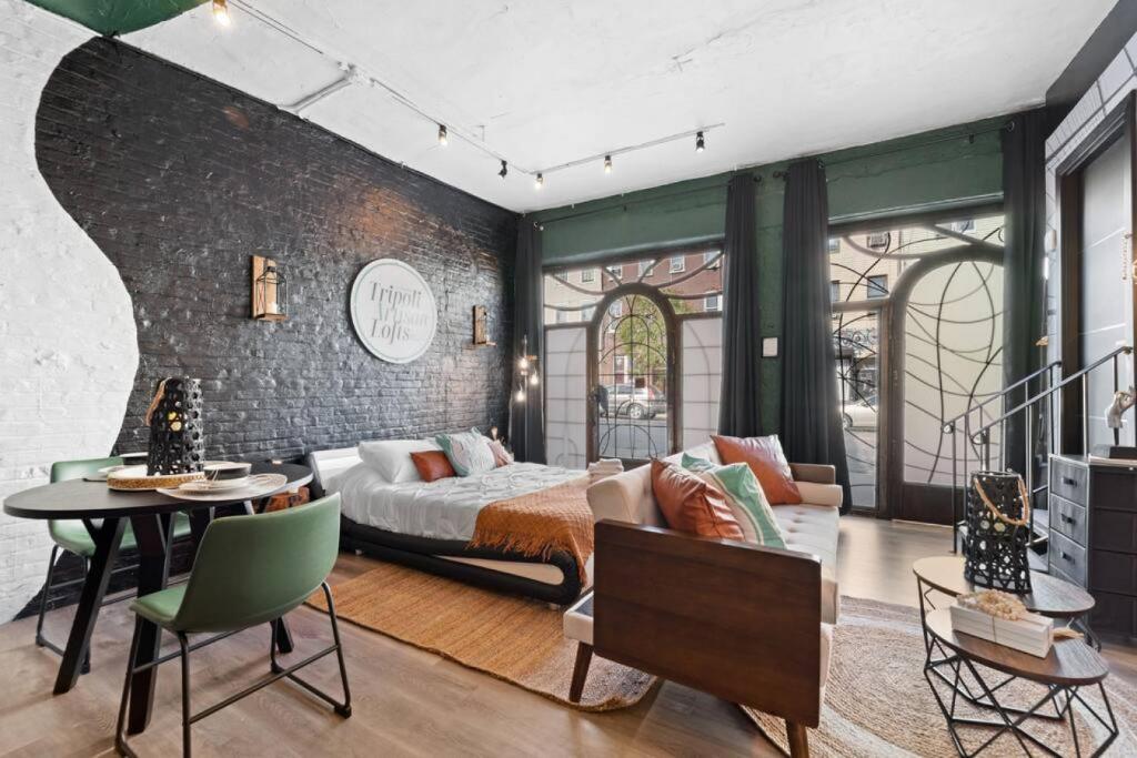 a bedroom with a bed and a couch and a table at Tripoli Artisan Lofts - Designer Bushwick Lofts with Rooftop Terrace in Brooklyn