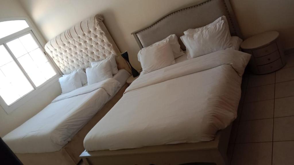 a white bed in a bedroom with a window at Al Ahmer Apartments in Dubai
