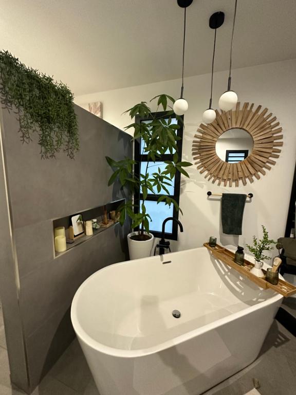 a white bath tub in a bathroom with a mirror at La Parenthèse chez Seb et Gwen in Le Tampon