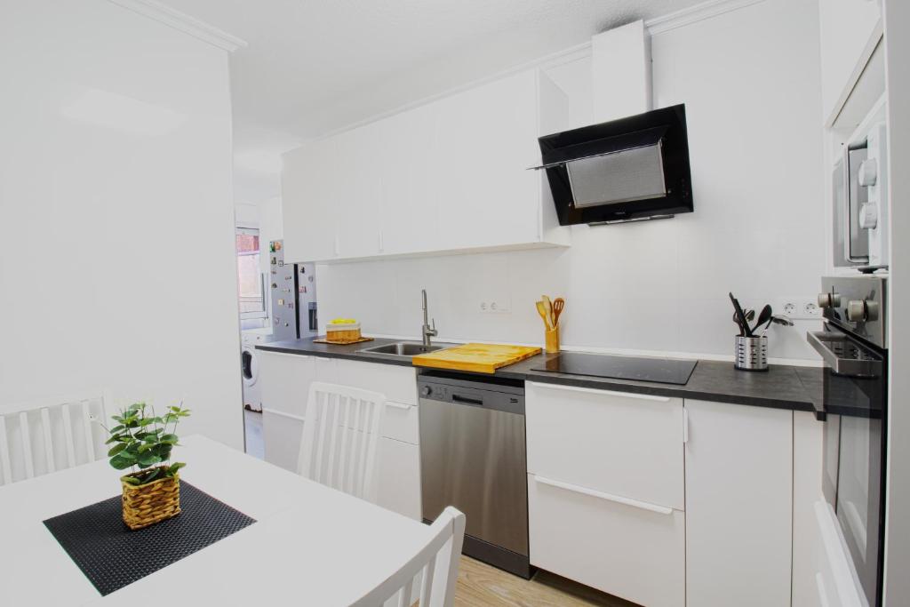 a kitchen with white cabinets and a white table at Entre Playa y Puntal in Somo