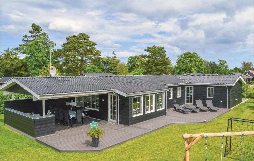 a black house with a deck in a yard at Holiday Home Hadsund 09 in Nørre Hurup