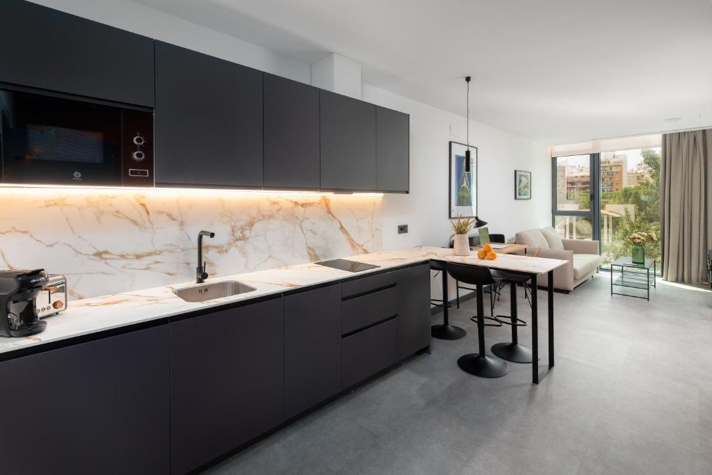 a kitchen with black cabinets and a table in it at Calatrava by Alma Suites in Valencia
