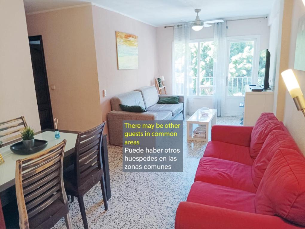 a living room with a red couch and a table at Habitaciones en Apartamento compartido DELICIAS ROOM Cerca del Mar, Aeropuerto, Ave y Metro in Málaga