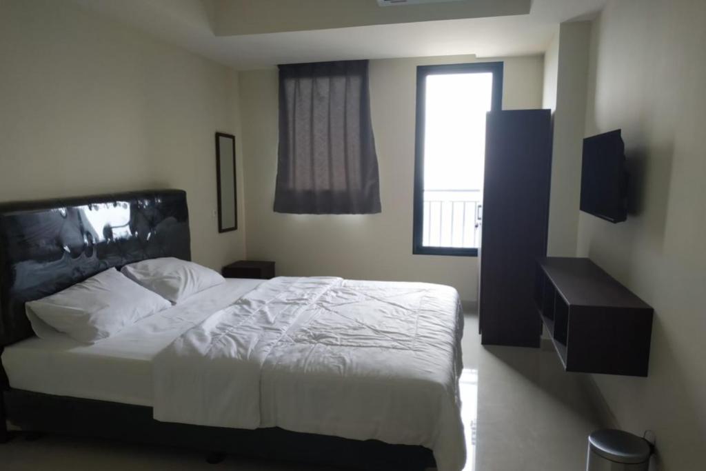 ein Schlafzimmer mit einem weißen Bett und einem Fenster in der Unterkunft OYO Life 92745 The Margo Monthly Stay in Depok