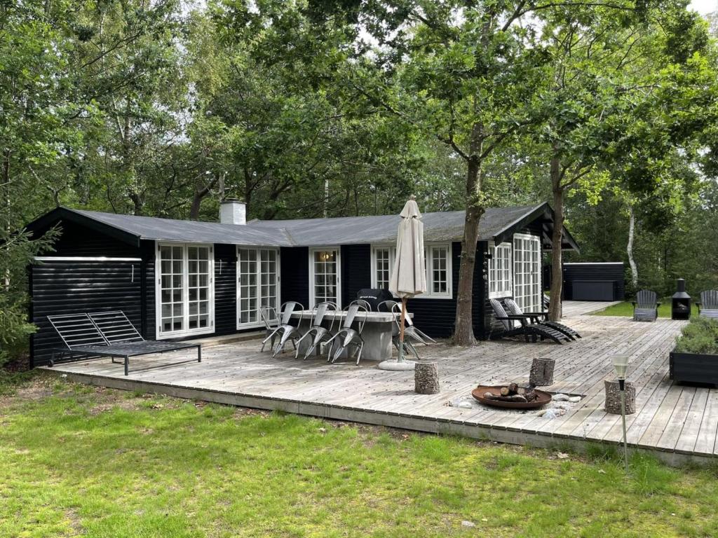 eine schwarze Hütte mit einer Terrasse und einer Terrasse in der Unterkunft Holiday Home Torben - 750m from the sea in Sealand by Interhome in Nykøbing Sjælland