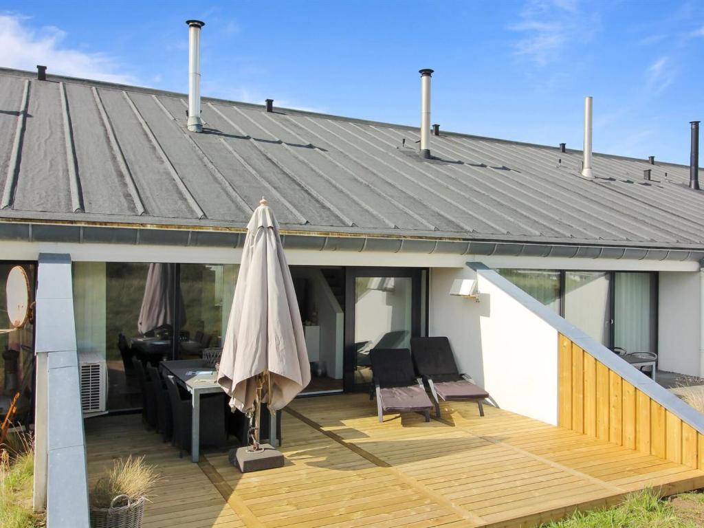 a patio with an umbrella on a wooden deck at Apartment Virpi - 1km from the sea in NW Jutland by Interhome in Blokhus