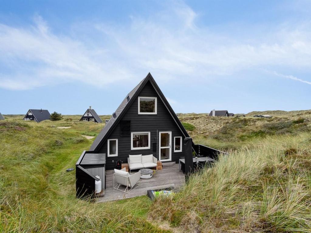 een zwart huis met een terras in een veld bij Holiday Home Pauli - 350m from the sea in NW Jutland by Interhome in Pandrup