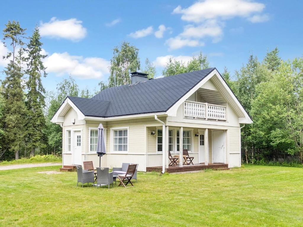 a white house with a black roof on a yard at Holiday Home Villa vuorso by Interhome in Raanujärvi