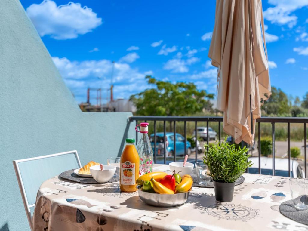 - une table avec un bol de fruits et un parasol dans l'établissement Studio Le Lagon Bleu-4 by Interhome, au Grau-du-Roi