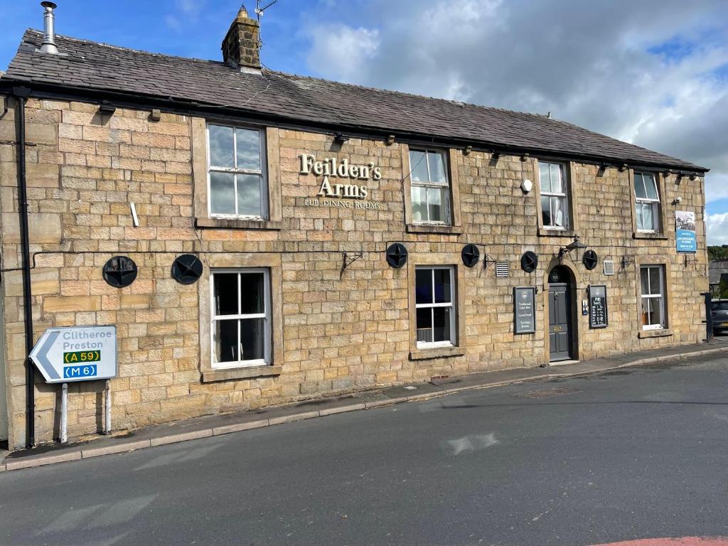 un viejo edificio de ladrillo al lado de una calle en Feildens Arms & Hotel, en Balderstone