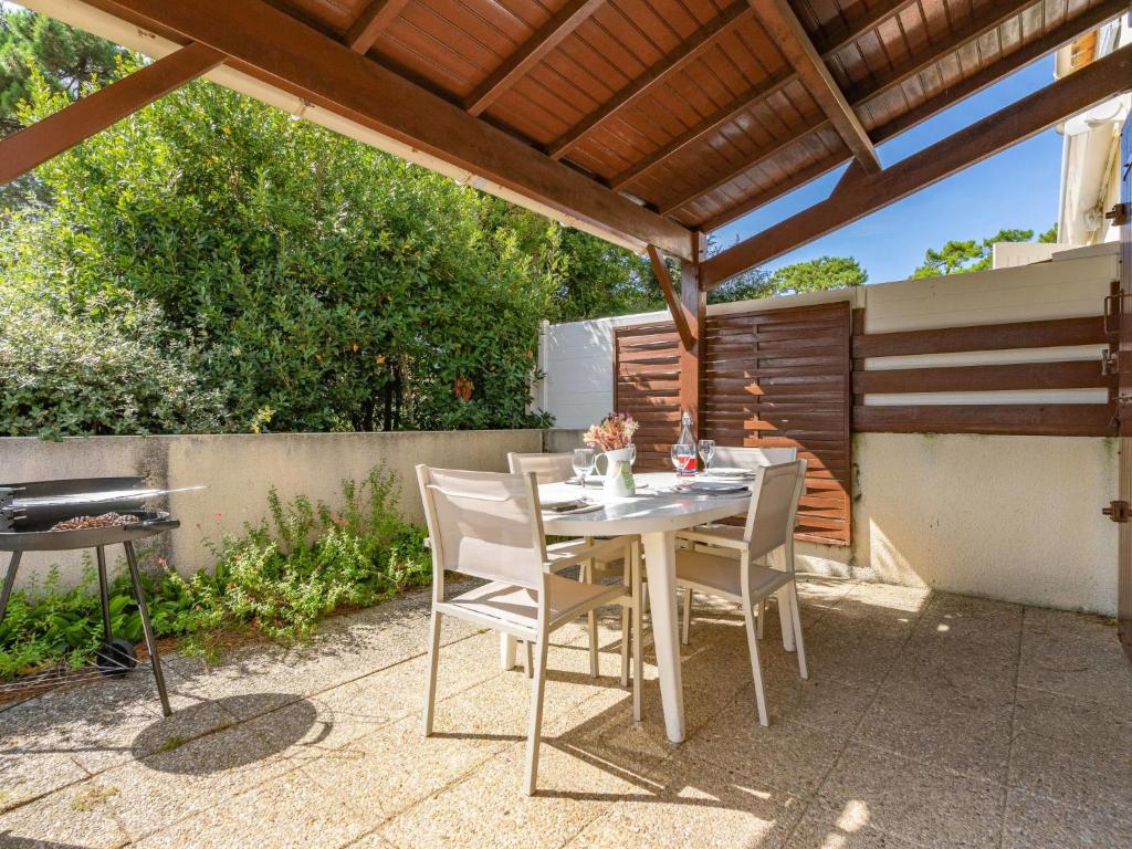 a patio with a table and chairs under a pergola at Holiday Home Les Jardins de la Palmyre-3 by Interhome in Les Mathes