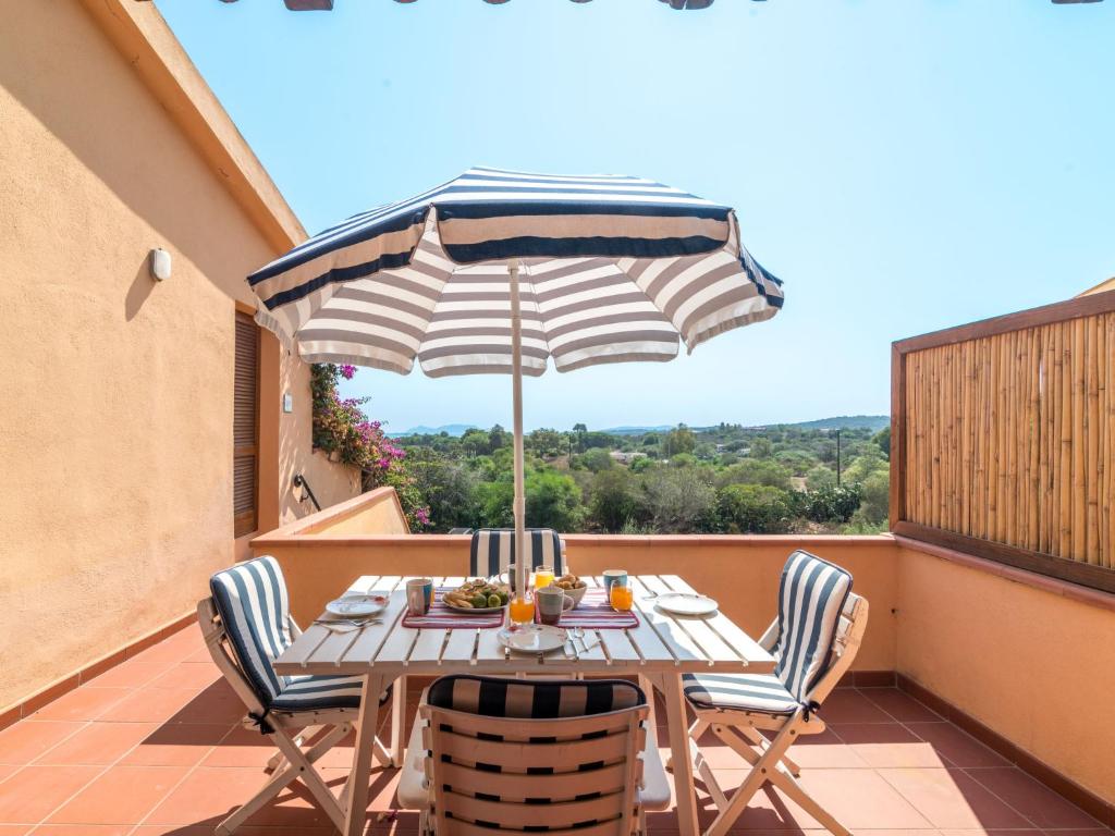 a table and chairs on a balcony with an umbrella at Apartment Arcobaleno by Interhome in Porto Istana