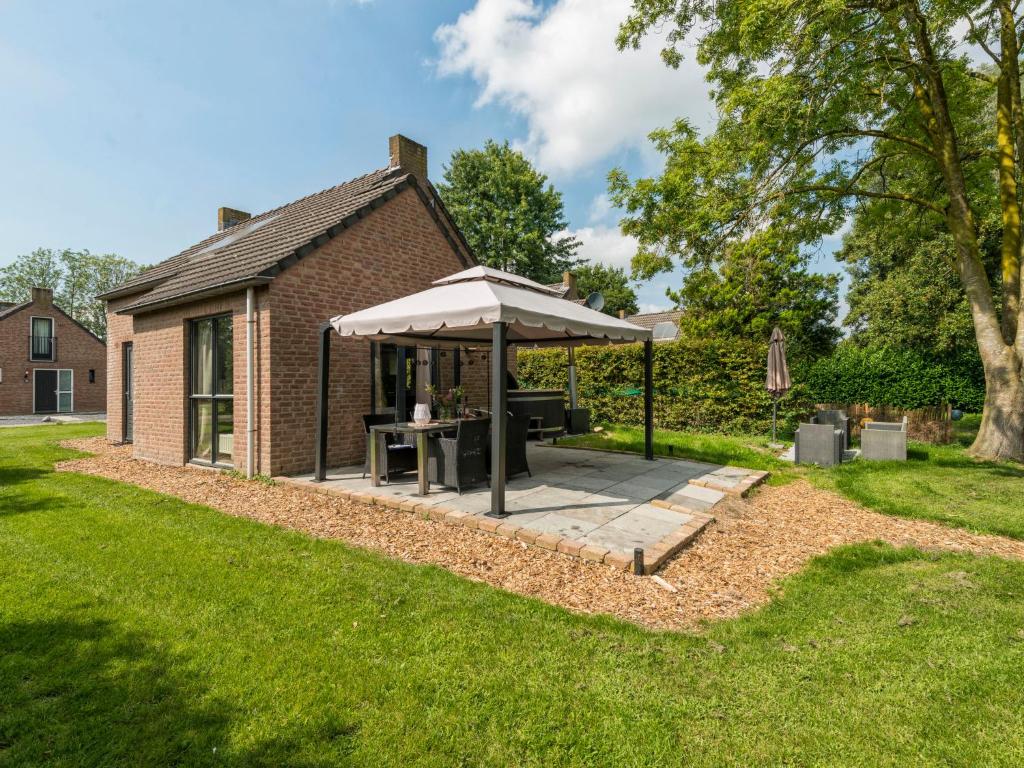 Ewijk的住宿－Holiday Home Forest Cottage Ewijk incl- hot tub by Interhome，一个带桌子和遮阳伞的庭院