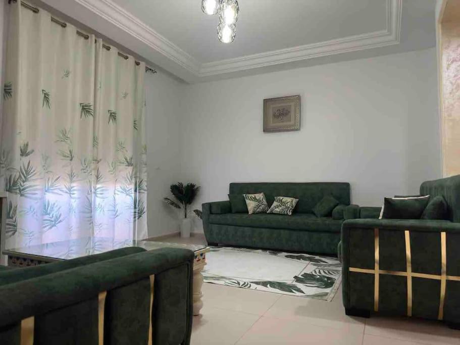 una sala de estar con 2 sofás verdes y un sofá en Appart.kelibia côté la plus belle mer de Tunisie, en Kelibia