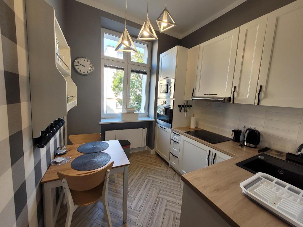 a kitchen with white cabinets and a table with chairs at Apartament Dworcowa 100 m do PKP in Kołobrzeg