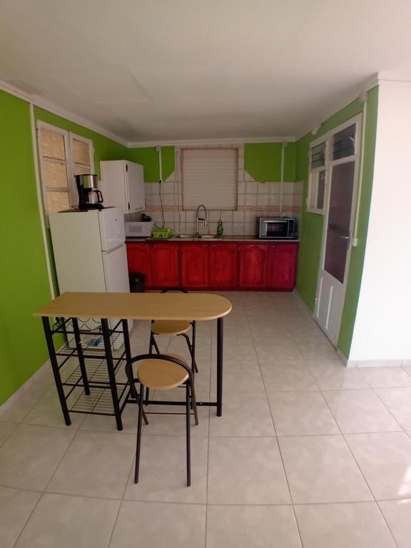 a kitchen with green walls and a table and chairs at Résidence Mathurin in Anse-Bertrand