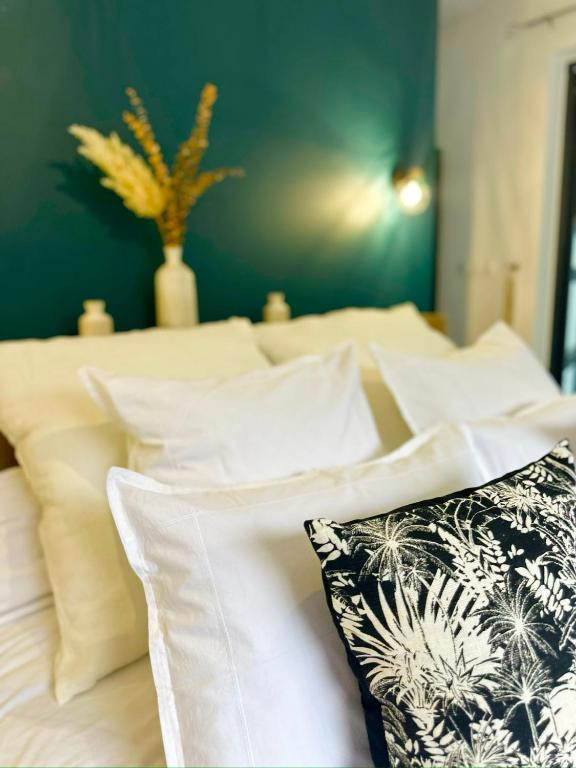 a bed with white pillows and a green wall at La Parenthèse chez Seb et Gwen in Le Tampon