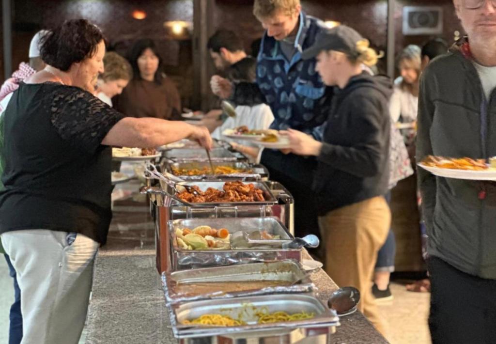 a group of people standing around a buffet with food at Angelina Wadi Rum camp in Wadi Rum