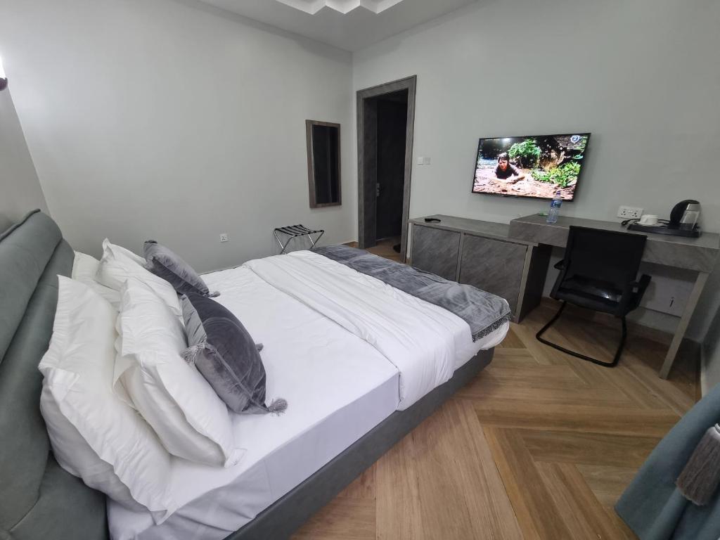 Dormitorio con cama, escritorio y TV en Solace Suites and Homes Maiduguri, en Maiduguri