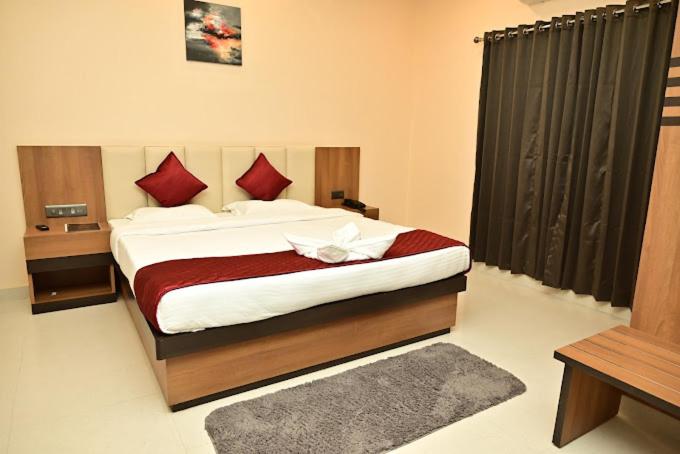 a bedroom with a large bed with red pillows at Heritage Suites in Jorhāt