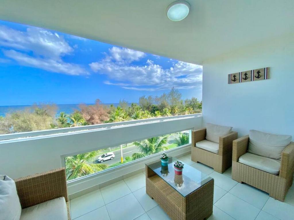 a living room with a large window with a view of the ocean at Charming Ocean View Apt Pool in La Francia