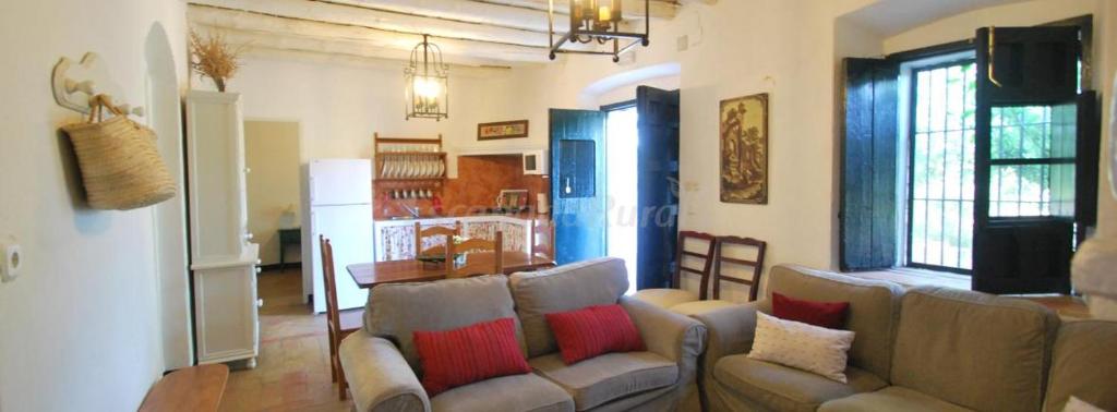 sala de estar con 2 sofás y cocina en Finca La Vicaria Alameda, en Zufre