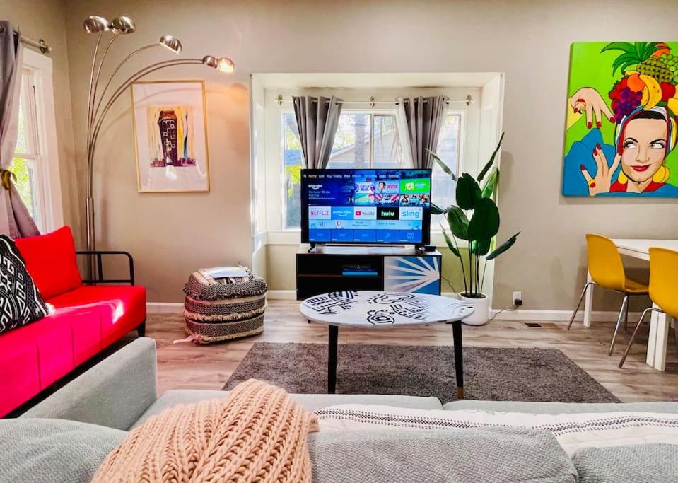 a living room with a red couch and a flat screen tv at Artists Bungalow ARCADE King Beds near the beat in Sacramento