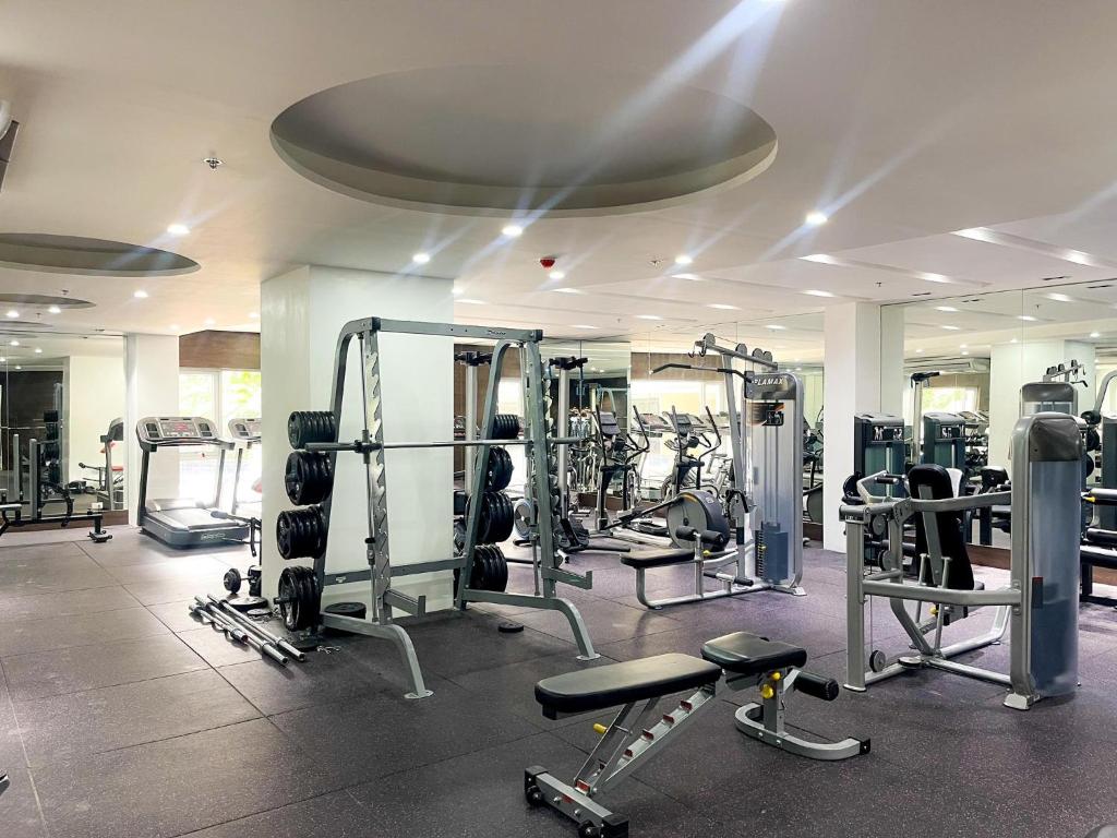 a gym with several tread machines in a room at Sunshine 100 Stylish Condo by Homexperience in Manila
