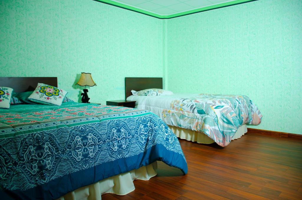 um quarto com 2 camas e piso em madeira em HOSTAL SALARCITO em Uyuni