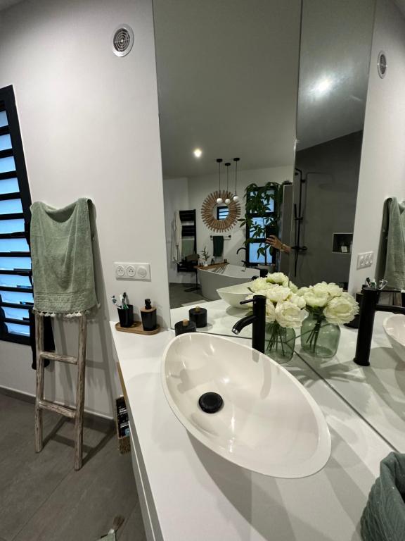 a bathroom with a sink and flowers on a counter at La Parenthèse chez Seb et Gwen in Le Tampon