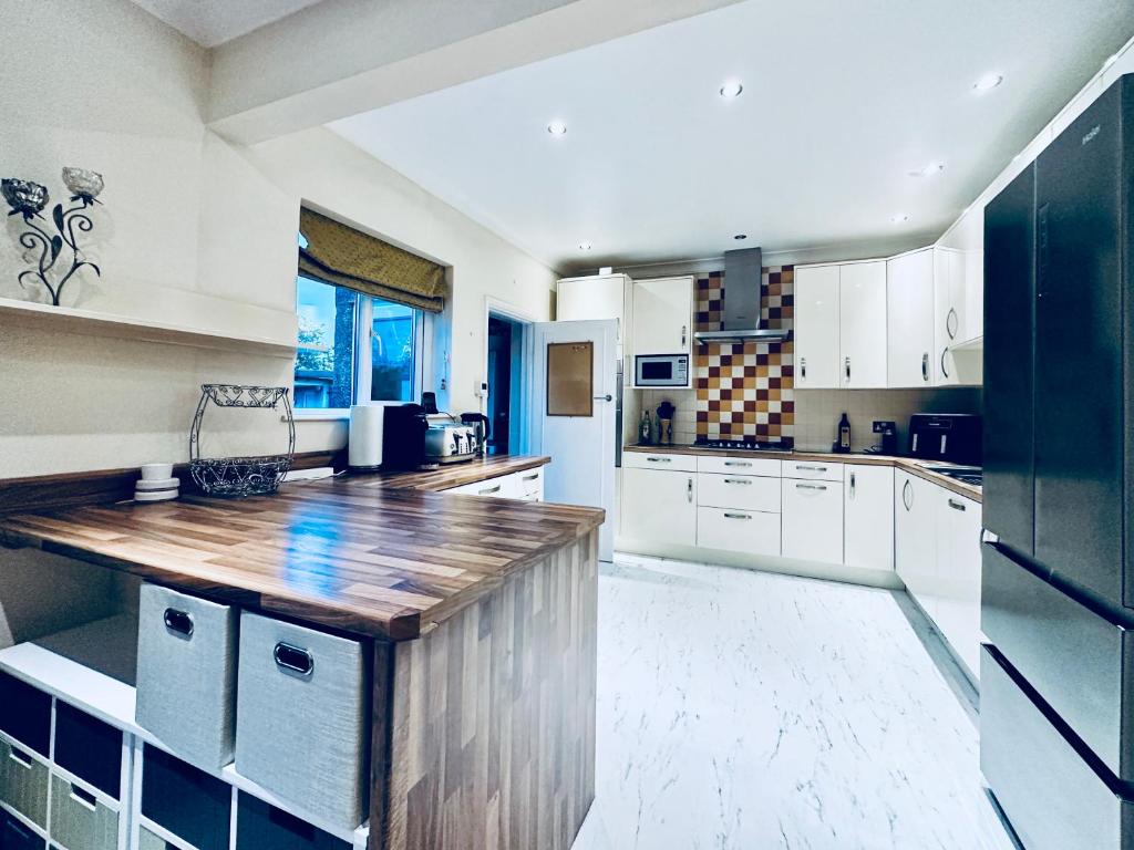 a kitchen with white cabinets and a wooden counter top at Zoya’s Place in Harrow in Pinner